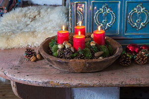 Advent wreath with red candles and moss in a wooden bowl