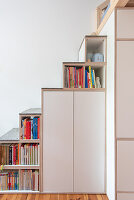 Staircase constructed with cupboards and bookshelves in space below