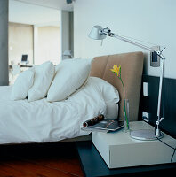 Contemporary open plan bedroom with bed bedside table home system control panel and Tolomeo Terra reading lamps