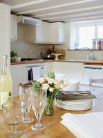 Cut roses and crockery with wineglasses on kitchen table
