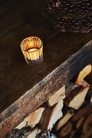 Teelicht brennt in einem Glashalter auf dem Kaminsims über den Holzscheiten in einer Holzhütte in den Bergen von Sirdal, Norwegen