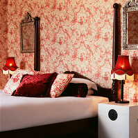 Rot-weiß gemusterte Tapete mit rotem Dekor und einem Doppelbett in einem Schlafzimmer