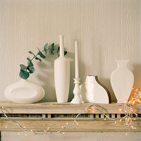 Detail of white vases and Christmas decorations on a wooden mantelpiece