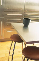 Close up of breakfast bar with chrome stools upholstered in brown leather