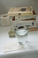 Glass of water and books on bedside table