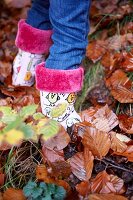 Nahaufnahme eines Mädchens mit Gummistiefeln im Laub, Herbst, Haslemere, Surrey, England