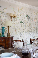 View over covered dining table to console and wallpaper with bird motif
