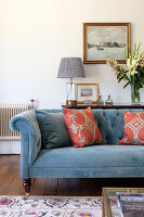 Blue upholstered sofa with cushions, console behind in living room