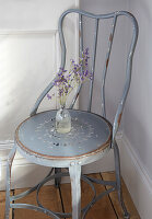 Vintage metal chair with flowers in glass vase