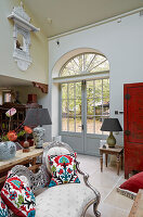 Living room with high window, colorful accent cushions and red door