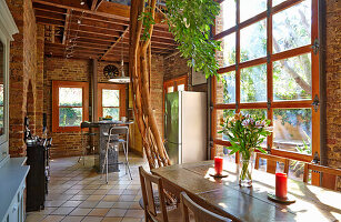 Dining area in open plan room with brick walls and tree