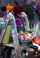 Herbstdekoration mit Blumen und Obst auf alter Holzleiter