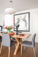 Dining room with grey upholstered chairs, drawing with bunny art on the wall