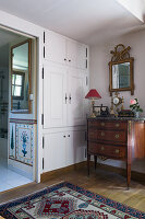Antique chest of drawers and fitted cupboards in bedroom corner
