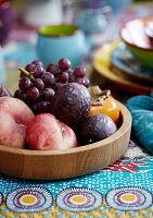 Fruit bowl with grapes and peaches on a colourful patterned tablecloth