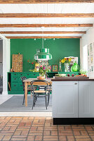 Kitchen with green wall, wooden beams and terracotta tiled floor