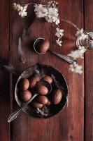 Vintage bowl with chocolate eggs and feathers