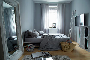 Large mirror and double bed in bedroom with grey blue walls