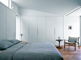 King-size bed in light bedroom with built-in wardrobes