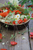 Earthenware bowl with water, filled with corn poppies, elderflowers, lady's mantle, wild strawberries and white shrub roses "Snow White