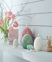 Egg-shaped candles in pastel shades and a bouquet of tulips