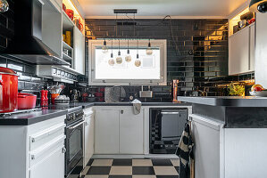 A black-and-white kitchen with red utensils