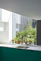 Maßgefertigte Küche mit grüner Front vor Fenster mit Gartenblick