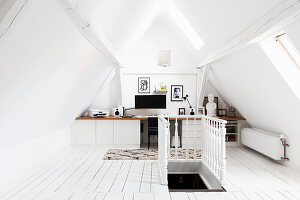 Attic workspace with white floorboards and wooden banisters