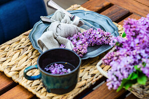 Frühlingsgedeck mit lila Fliedern auf Tisch im Freien