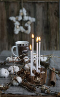 Four candles in cinnamon candlesticks with larch twigs and cotton, coffee cup with deer motif