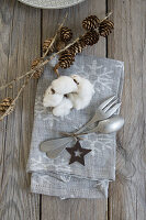 Place setting with a napkin, cutlery, star, cotton, and larch twigs