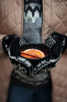 Gloved hands holding cup with glögg (Scandinavian mulled wine)