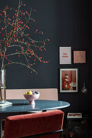 Chair with pink cover around round table in room with black wall and stucco