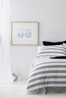 A coastal style bedroom with white panelled walls, a curtain and a white floor