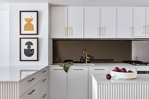 An apartment kitchen with fluted panel joinery, brushed gold tapware and marble bench tops.
