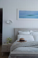 Doppelbett aus Mangoholz vor weiß gestrichener Holzverkleidung im Schlafzimmer