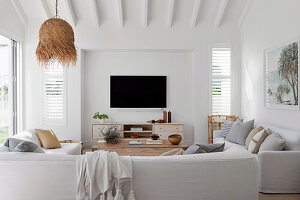 Sitzbereich mit Polstersofa und Fernseher im Wohnzimmer mit weißen Wänden