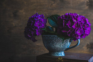 Ceramic cup with fresh hydrangea flowers in interior