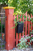 Rot gestrichener Holzzaun mit Briefkasten
