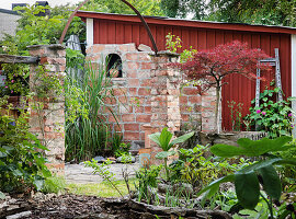 Walls of recycled bricks in a garden with lush elephant grass (Miscanthus giganteus)