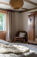 Leather armchair next to wardrobe in country-style bedroom