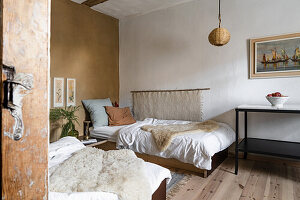 Two single beds with sheepskin throws in a rustic guest room
