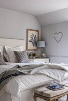 Unmade bed in room with heart, in a cottage