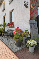 Container garden and bench in front of white painted brick facade