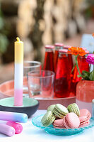 Macarons, colorful DIY candles and drinks on garden table