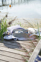 Wooden jetty at the lake with cushions and picnic items in summer