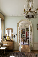 An antique chandelier in a room with open French doors