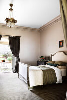 Antique double bed with upholstered headboard and footboard in bedroom with terrace access