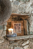 Framed black and white photo and candle in natural stone wall niche