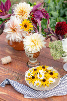 Flower arrangement with dahlias, Black-eyed Susans, and daisies on garden table